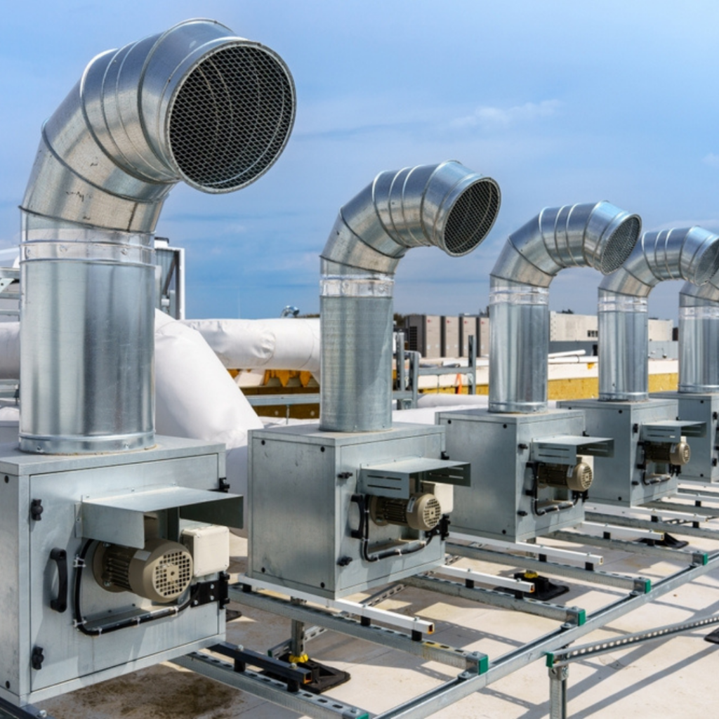 Alignement de caissons d'extraction d'air et de gaines de ventilation industrielle installés sur le toit d'un bâtiment professionnel.